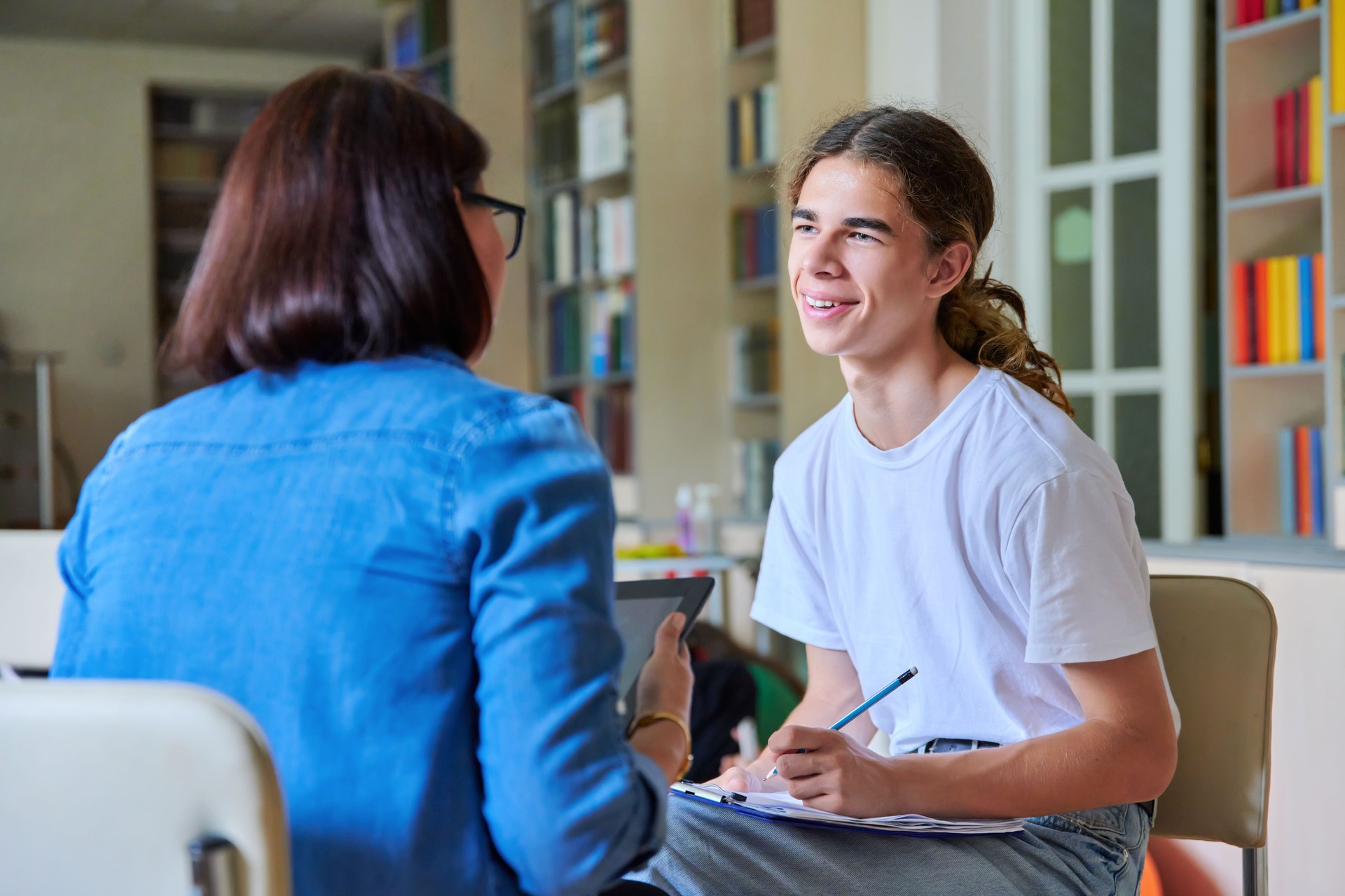 Woman school psychologist teacher talking and helping student, male teenager